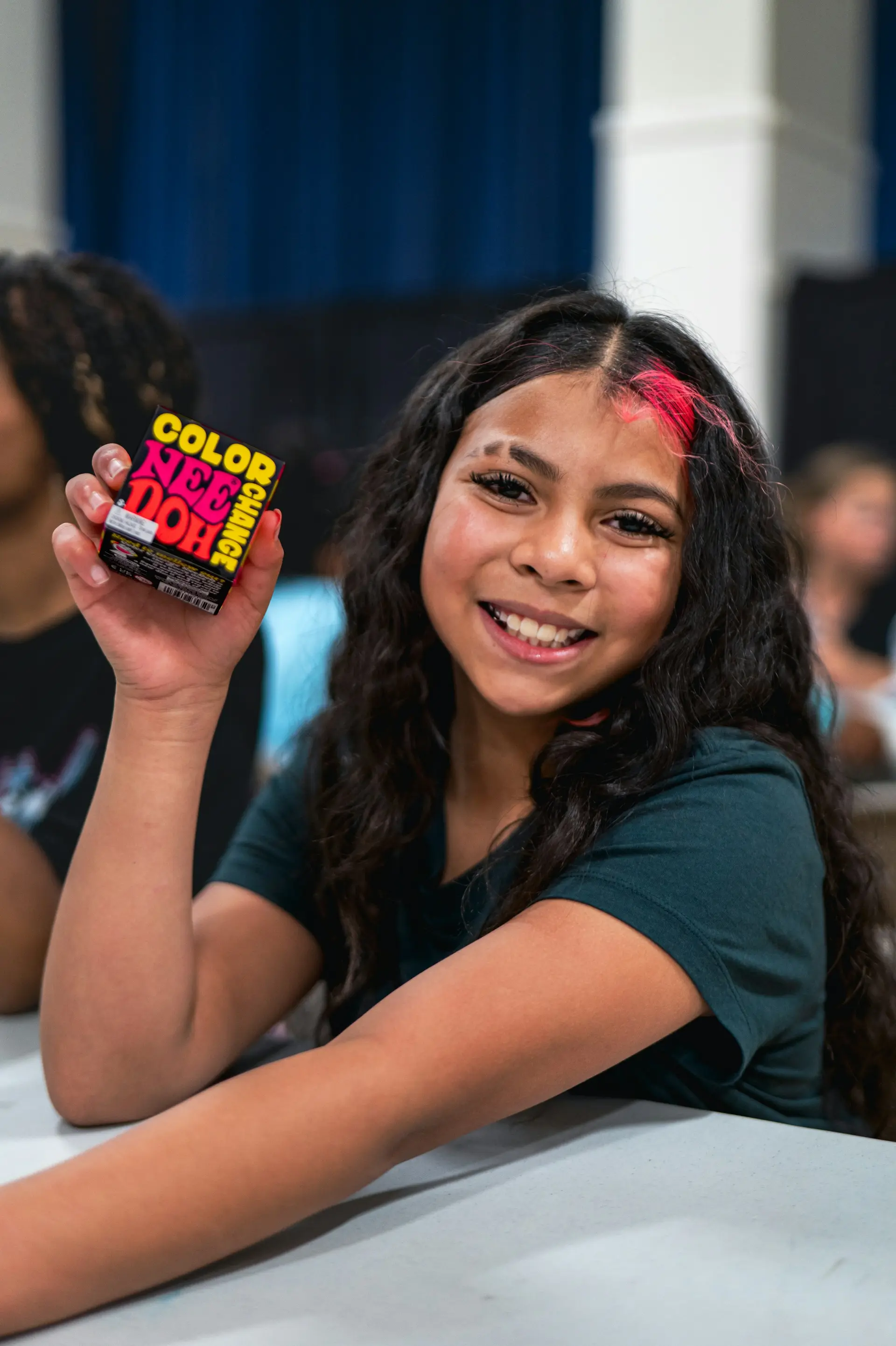 A smiling girl holding up a prize at a community event