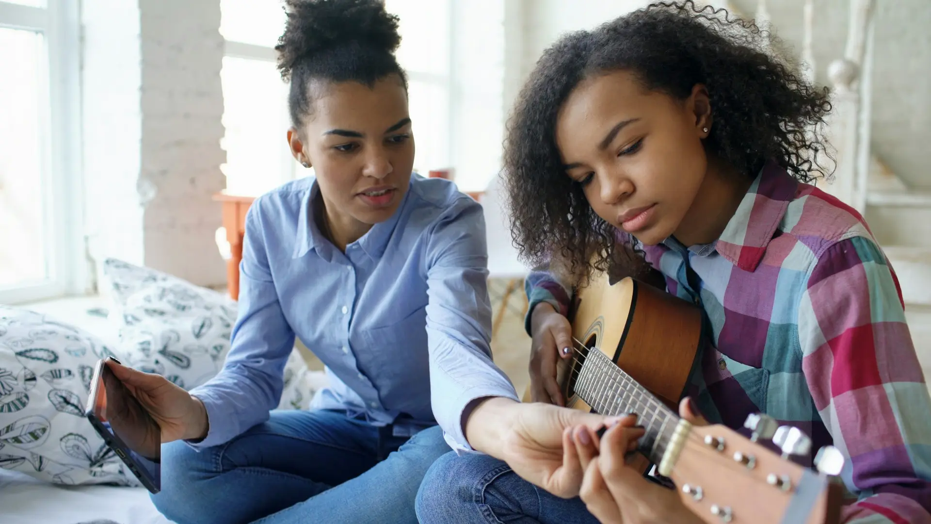 A mentor teaching a teenage girl to play guitar