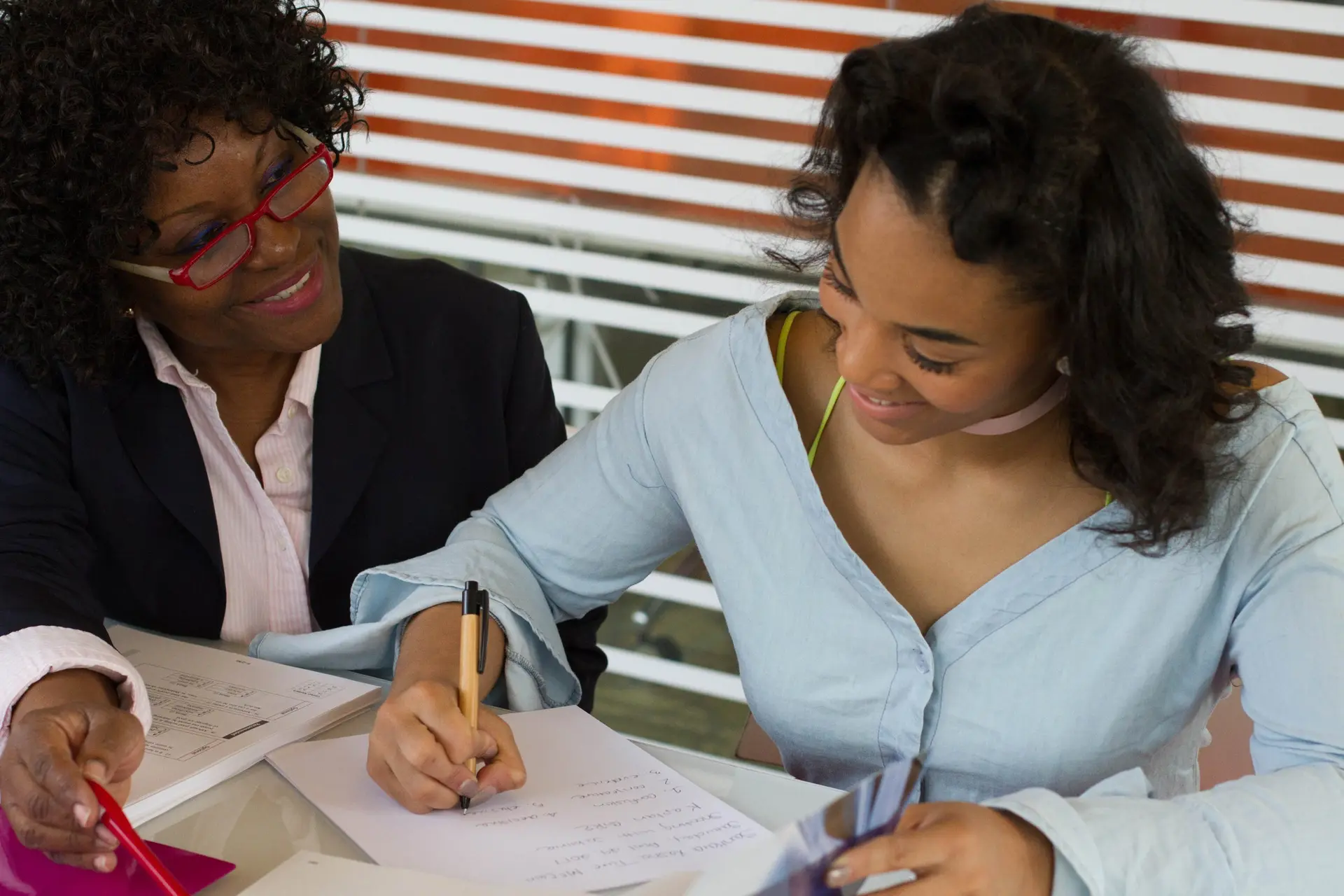 A mentor and a young woman working through notes together at a table