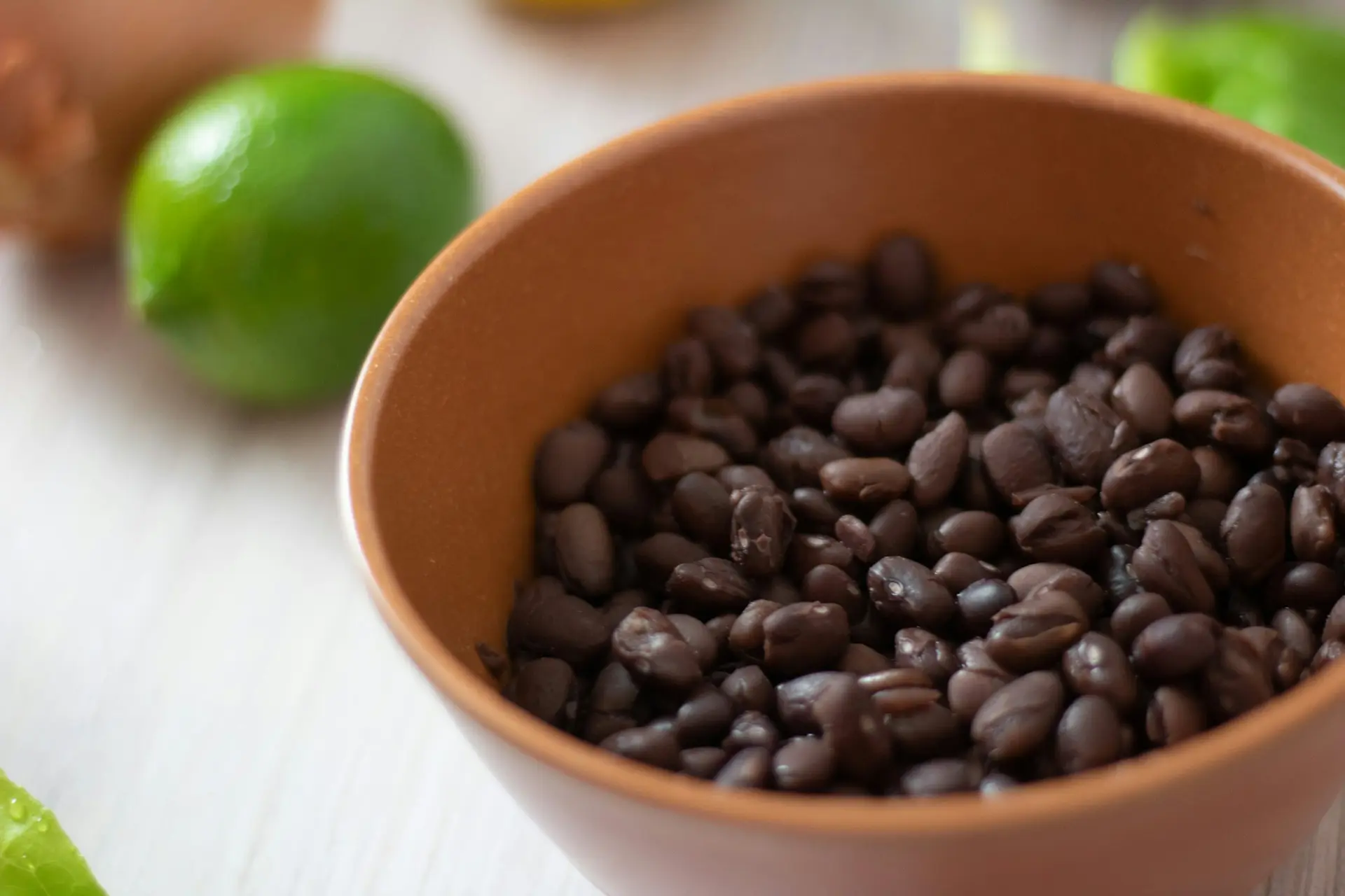 A bowl of black beans beside fresh limes